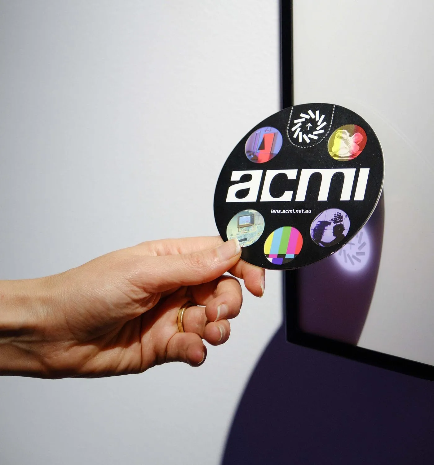 A visitor holding The Lens against an interactive display at ACMI.
